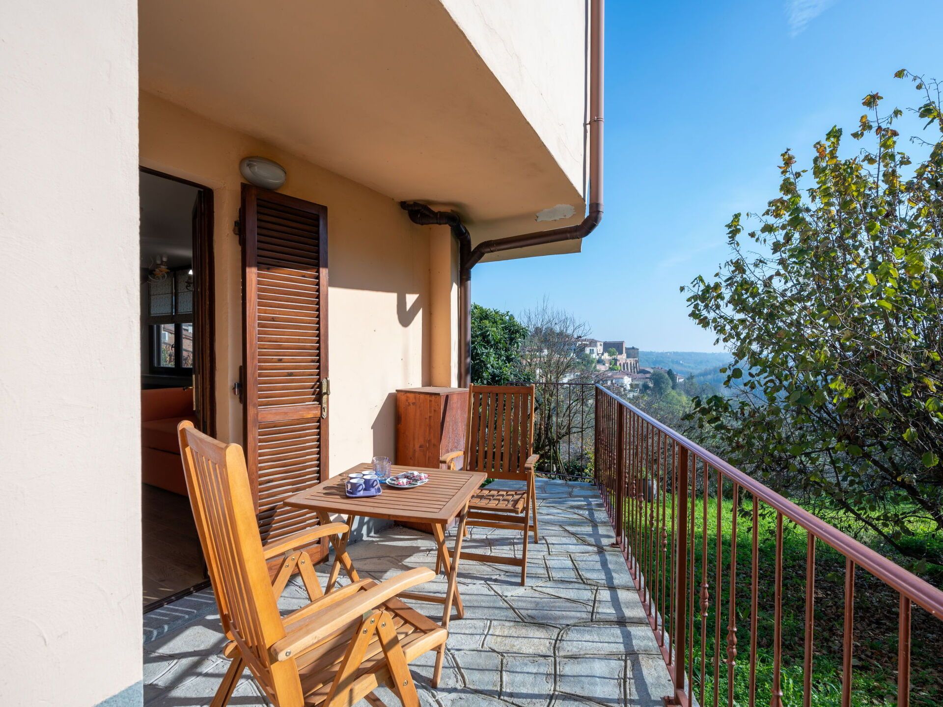 Un balcón con muebles de madera y vistas del paisaje circundante.