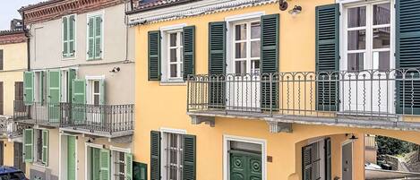 A row of terracotta-roofed buildings with green shutters and balconies.
