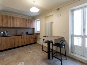 Cozinha moderna com armários de madeira, bancada preta e mesa de jantar para duas pessoas.