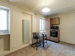 Cozinha compacta com mesa e cadeiras, forno embutido e micro-ondas.