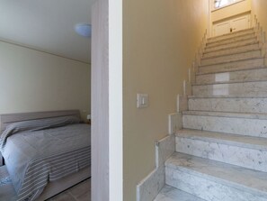 A bedroom with a bed and a staircase with marble steps. - Cosy apartment for 6 guests with pool, WIFI, balcony and panoramic view (Castagnole Monferrato)