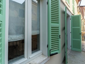 Um edifício com janela e porta com persianas verdes.