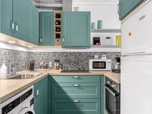 A kitchen with teal cabinets, a microwave, a sink, and a dishwasher.