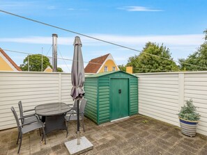 A patio with a table and chairs, a green shed, and a potted plant. - "Maureen" - 150m from the sea by Interhome (Haderslev)