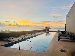 Ein Schwimmbad mit Liegestühlen und Blick auf den Sonnenuntergang.