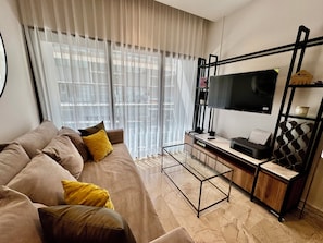 A modern living room with a sofa, a glass coffee table, a TV on a black stand, and a bookshelf. - The Best Place in Playa del Carmen! (Playa del Carmen)