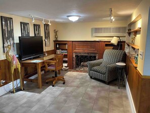 A living room with a flat-screen TV, wooden furniture, a fireplace, and a ceiling fan.