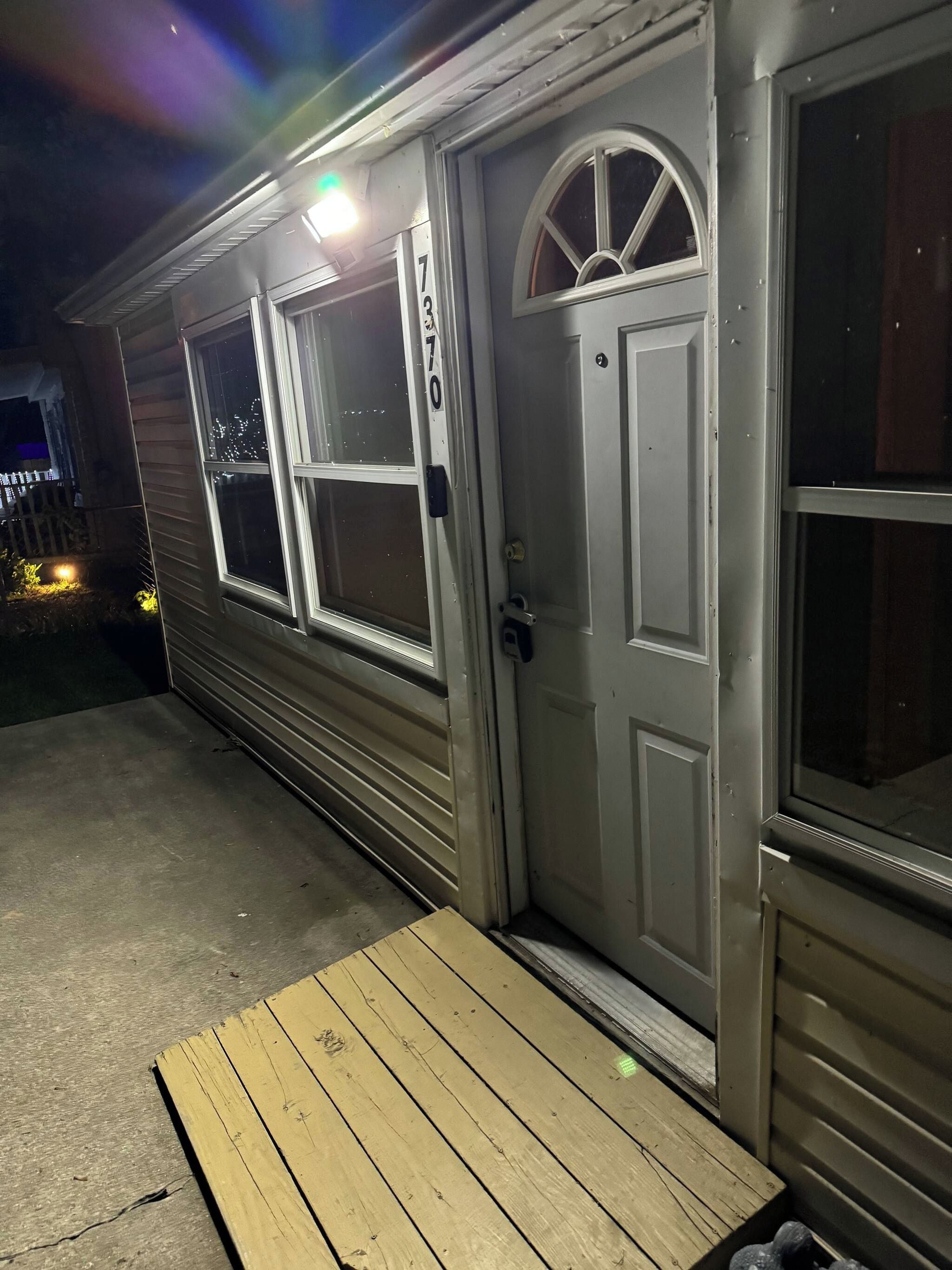 Una casa con puerta principal, dos ventanas y un porche.