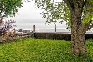 Un espace verdoyant avec un arbre, une clôture en bois et une vue sur la mer.