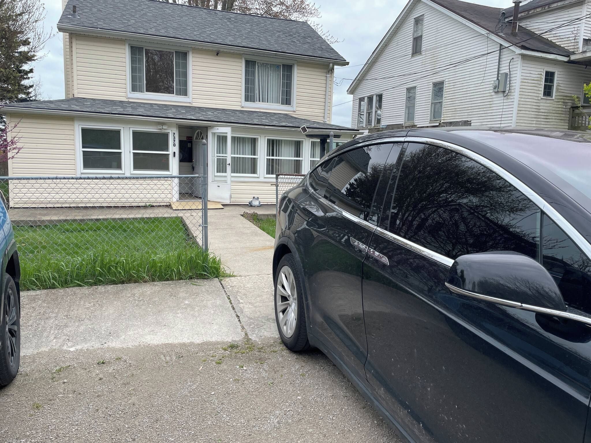 A residential driveway with a parked car and a house with a garage door.