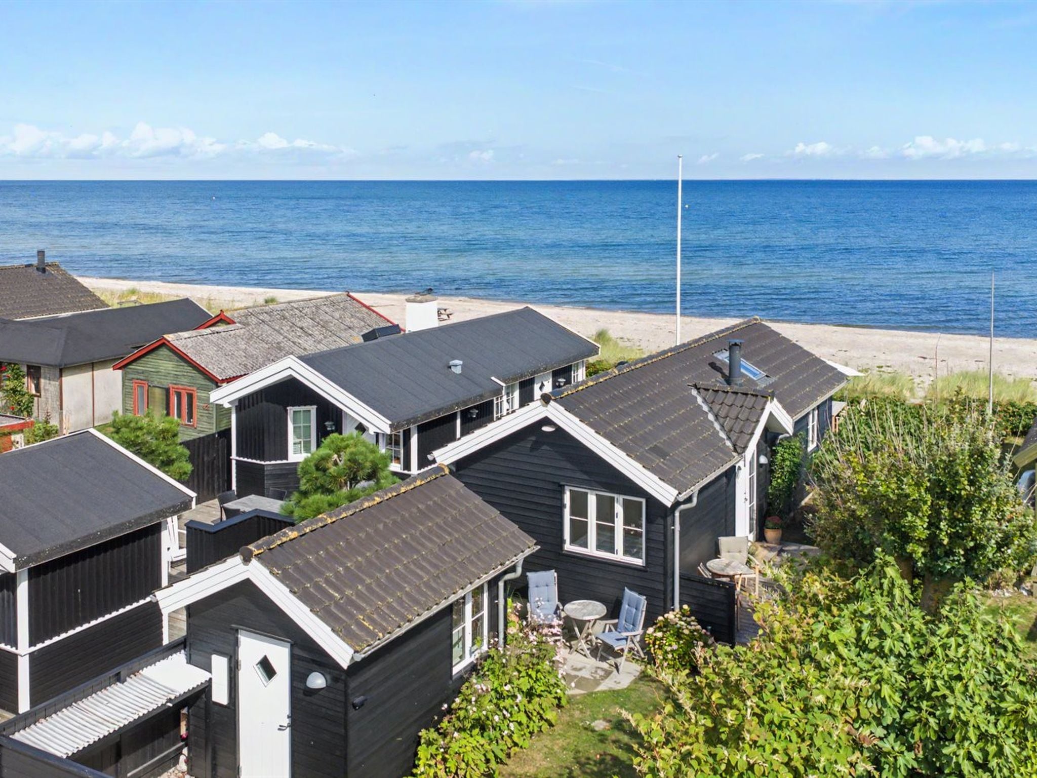 A coastal residential area with multiple houses, some with attached garages, and a clear view of the ocean.