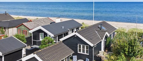 A coastal residential area with multiple houses, some with attached garages, and a clear view of the ocean.