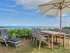 An outdoor seating area with a table and chairs, a large umbrella, and a view of the ocean. - "Joachim" - 10m from the sea by Interhome (Otterup)