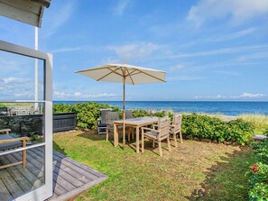 A patio with a table and chairs, an umbrella, and a view of the ocean. - "Joachim" - 10m from the sea by Interhome (Otterup)