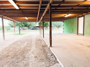 Een overdekte sportzaal met een baan van aarde, houten balken en een groene wand.