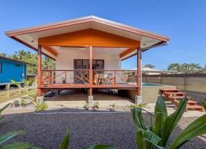 A two-story building with a covered porch, a pool, and a fenced area with picnic tables.