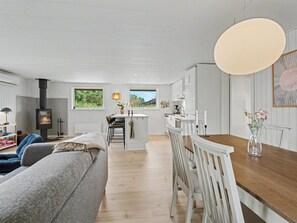 A modern living room with a sofa, a dining table with chairs, a kitchen area, and a fireplace. - "Trineke" - 400m from the sea by Interhome (Dannemare)