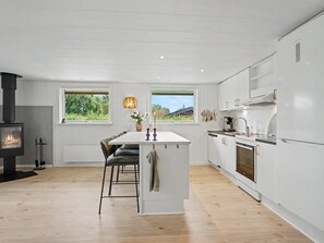 A modern kitchen with a central island, white cabinetry, and a wood-burning stove. - "Trineke" - 400m from the sea by Interhome (Dannemare)