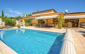 A swimming pool with lounge chairs and umbrellas, surrounded by a patio area with outdoor furniture. - Maison avec piscine privée (Vaison-la-Romaine)