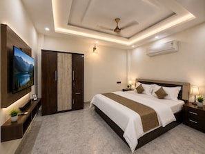 Quarto de hotel com cama grande, televisão na parede, guarda-roupa e ar condicionado.