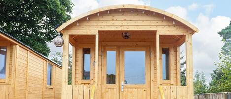 A wooden cabin with a curved roof, a door, and a window.