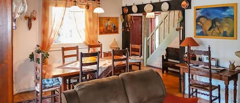 Un espace repas avec une table et des chaises en bois, un tapis à motifs et un escalier menant à un autre niveau.