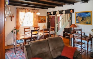 Ein Essbereich mit einem Holztisch und Stühlen, einem gemusterten Teppich und einer Treppe, die zu einer anderen Ebene führt.