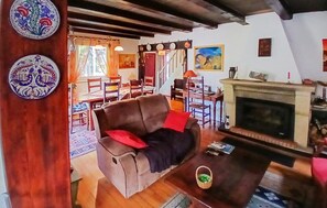 Un saló acollidor amb una llar de foc, zona de menjador amb mobles de fusta i plats decoratius a la paret.