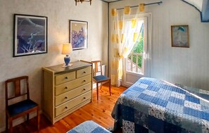 Ein Schlafzimmer mit einem Bett, einem Schminktisch, einem Stuhl und zwei Bildern an der Wand.