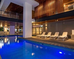A swimming pool with lounge chairs and a covered area with a wooden ceiling. - Brisbane City Views | 2BR Near South Bank & QPAC (South Brisbane)