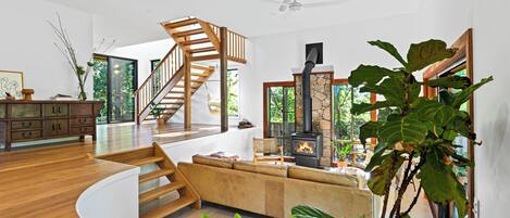 Un interior moderno con una escalera de madera, una chimenea y una planta grande.