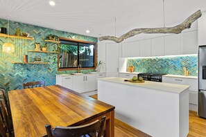 A modern kitchen with a herringbone tile backsplash, wooden cabinetry, and a central island.