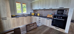 Eine moderne Küche mit Holzschränken, einem Bosch-Backofen und einem Fenster, das für natürliches Licht sorgt.