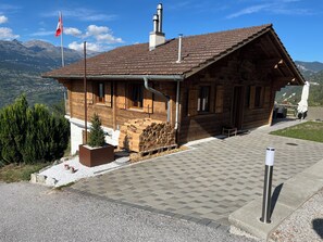 Eine Holzhütte mit einem Ziegeldach, einer Flagge und Blick auf Berge.