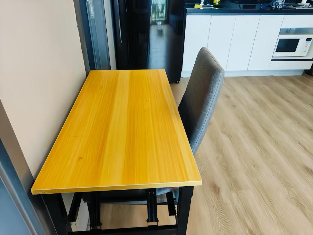Een eettafel met een stoel in een moderne keuken met witte kasten en een magnetron.
