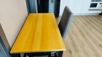 Een eettafel met een stoel in een moderne keuken met witte kasten en een magnetron.