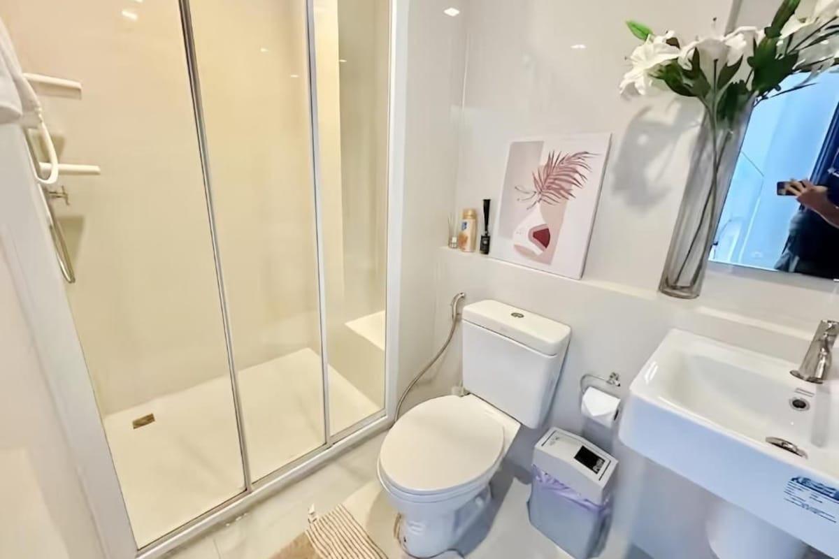 A modern bathroom with a glass-enclosed shower, a toilet, a sink, and a mirror.