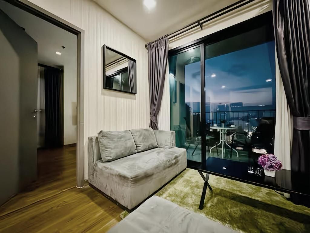 Una sala de estar con un sofá, una mesa de vidrio y vistas a la ciudad.