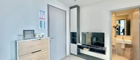 Une chambre moderne équipée d’un téléviseur à écran plat, d’une armoire intégrée, d’un miroir et d’une porte donnant accès à une salle de bain.