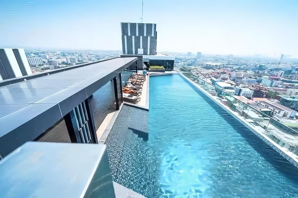 A rooftop infinity pool with a city view, modern architecture, and lounge seating.