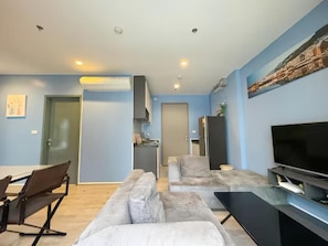 A modern living room with a sofa, TV, and a dining area. - The Base Central Pattaya (Muang Pattaya)