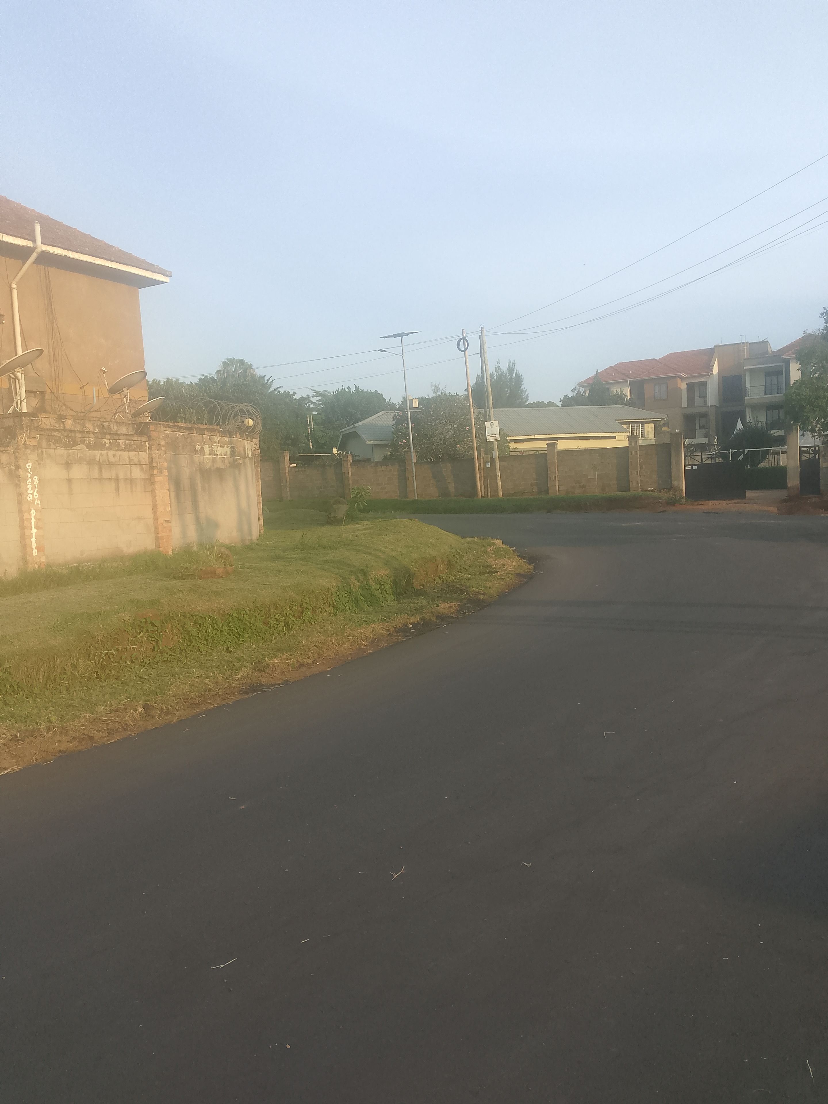 A residential street with houses, a paved road, and utility poles.