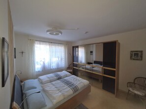 A bedroom with a bed, a chair, a wardrobe, and a ceiling fan.
