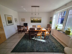 A dining area with a table, chairs, a rug, and artwork on the walls.