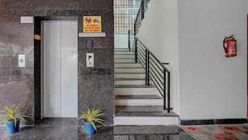 A hotel reception area with a marble counter, a fire extinguisher, and a staircase.