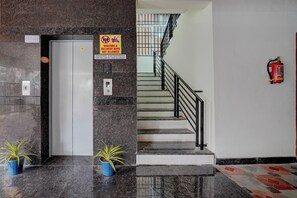 A hotel reception area with a marble counter, a fire extinguisher, and a staircase. - Townhouse Element Mall Bangalore (Bengaluru)