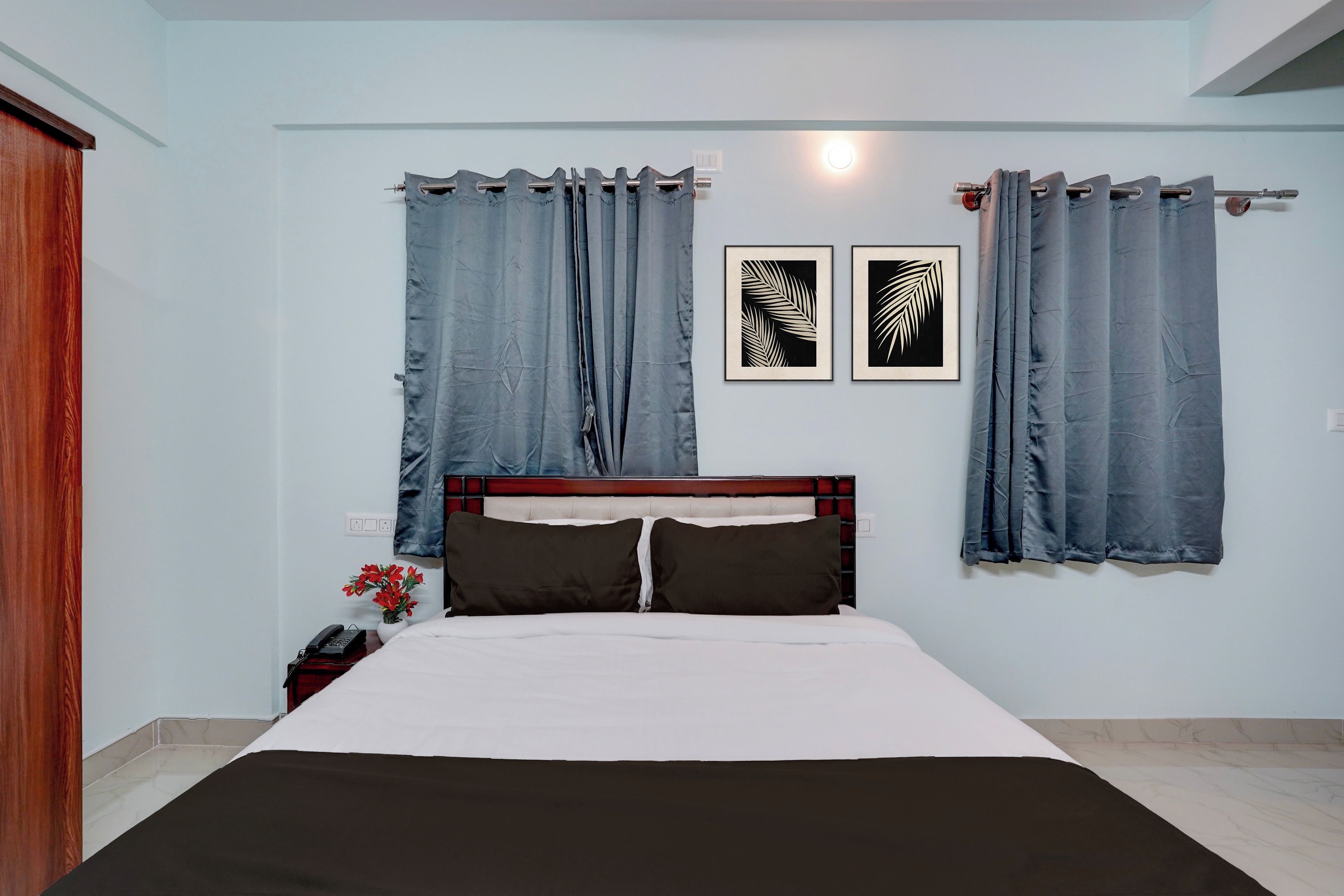 Un dormitorio con una cama, cortinas y dos cuadros en la pared.