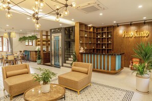 A hotel lobby with a reception desk, seating area, and a staircase. - Palo Santo Phu Quoc - Fireworks & Ocean (Phu Quoc)