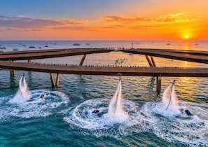 A bridge over water with multiple boats and jetskis creating water patterns. - Palo Santo Phu Quoc - Fireworks & Ocean (Phu Quoc)