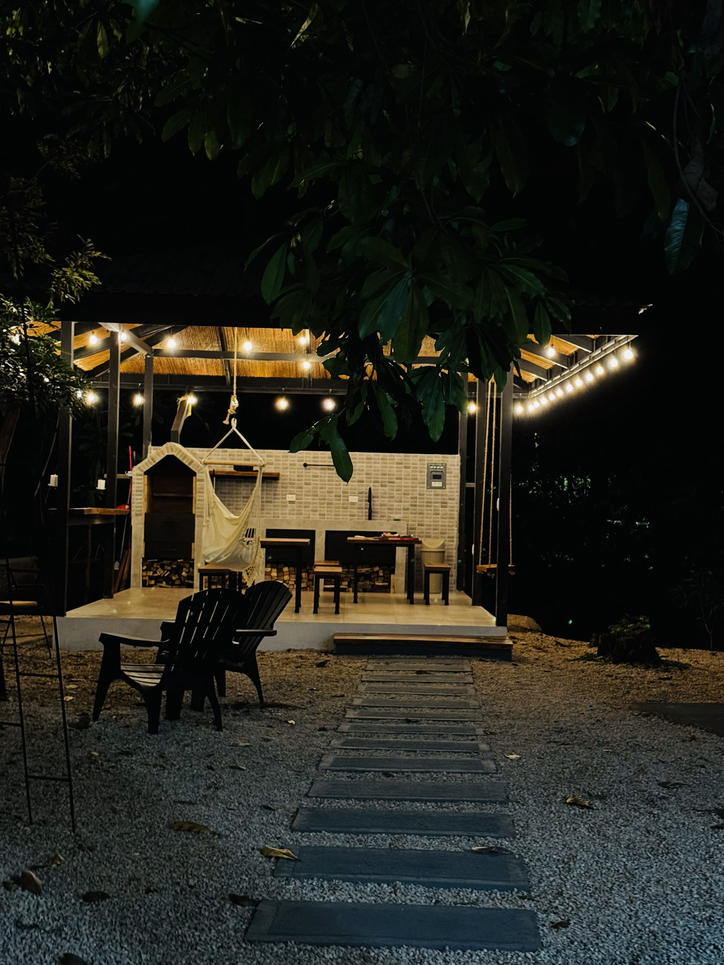Un espace extérieur aménagé avec un coin salon, une cheminée en briques, des tables et des chaises.